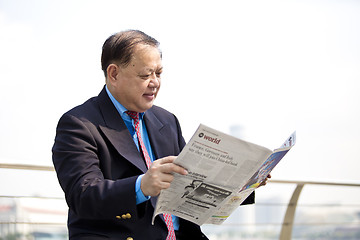 Image showing Asian businessman reading newspaper