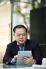 Image showing Asian businessman using tablet