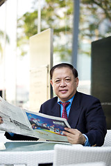 Image showing Asian businessman reading newspaper