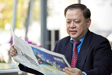 Image showing Asian businessman reading newspaper