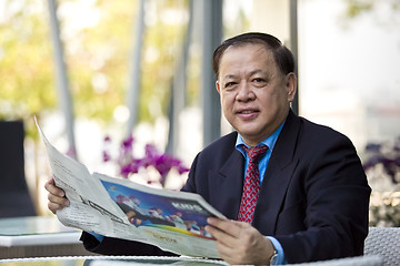 Image showing Asian businessman reading newspaper