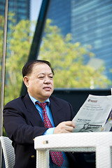 Image showing Asian businessman reading newspaper