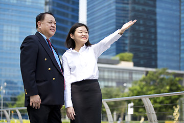 Image showing Asian businessman and young female executive pointing at a direction
