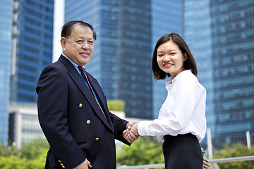 Image showing Asian businessman and young female executive shaking hands