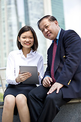 Image showing Asian businessman and young female executive using tablet