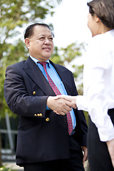 Image showing Asian businessman and young female executive shaking hands