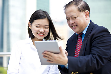 Image showing Asian businessman and young female executive using tablet