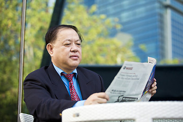 Image showing Asian businessman reading newspaper