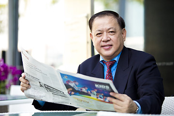 Image showing Asian businessman reading newspaper