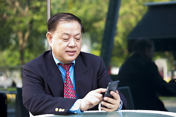 Image showing Asian businessman looking at smart phone