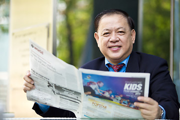 Image showing Asian businessman reading newspaper