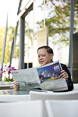 Image showing Asian businessman reading newspaper