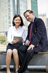 Image showing Asian businessman and young female executive using tablet