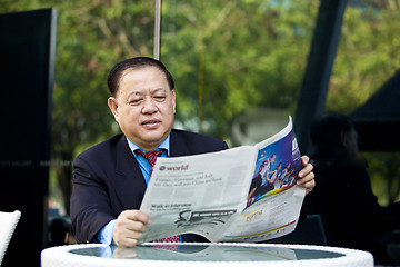 Image showing Asian businessman reading newspaper