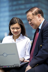 Image showing Asian businessman and young female executive using laptop