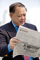 Image showing Asian businessman reading newspaper