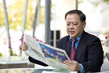 Image showing Asian businessman reading newspaper