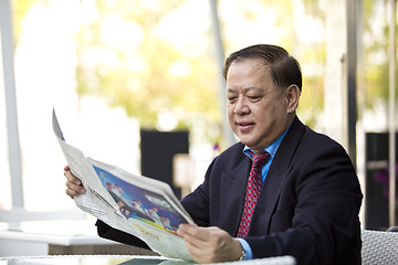 Image showing Asian businessman reading newspaper