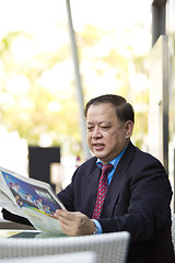 Image showing Asian businessman reading newspaper