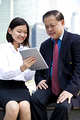 Image showing Asian businessman and young female executive using tablet