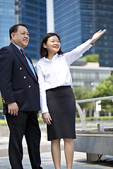 Image showing Asian businessman and young female executive pointing at a direction