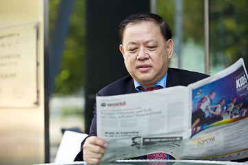 Image showing Asian businessman reading newspaper