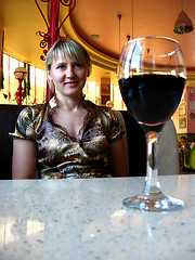 Image showing glass of red wine on the table and a girl