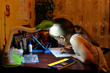 Image showing schoolgirl learns lessons at the table