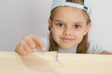 Image showing Girl twists the screw with an Allen key