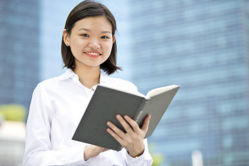 Image showing Asian young female executive holding book smiling