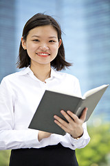 Image showing Asian young female executive holding book smiling