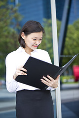 Image showing Asian young female executive holding file smiling