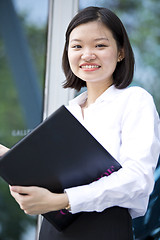 Image showing Asian young female executive holding file smiling