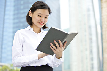 Image showing Asian young female executive holding book smiling