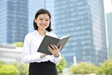 Image showing Asian young female executive holding book smiling