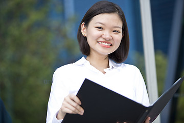 Image showing Asian young female executive holding file smiling
