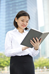 Image showing Asian young female executive holding book smiling