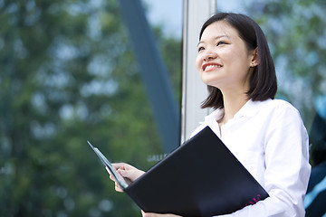 Image showing Asian young female executive holding file smiling