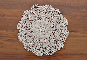 Image showing Lace doily on dark wood