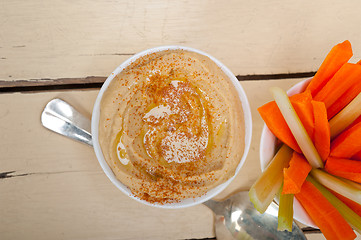 Image showing fresh hummus dip with raw carrot and celery 