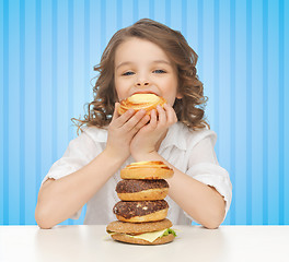 Image showing happy little girl eating junk food