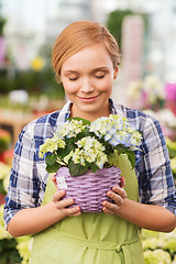 Image showing happy woman smelling flowers in greenhouse