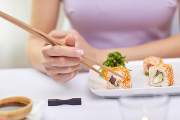 Image showing close up of woman eating sushi at restaurant