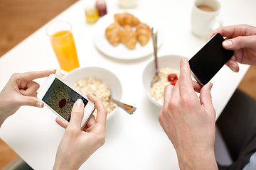 Image showing close up of couple with smartphones at breakfast