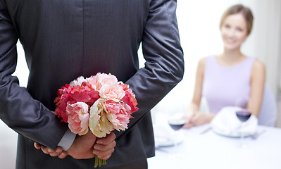 Image showing close up of man hiding flowers behind from woman