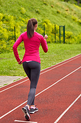 Image showing woman running on track outdoors from back
