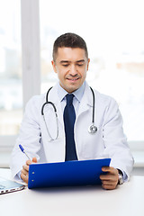 Image showing happy doctor with clipboard in office