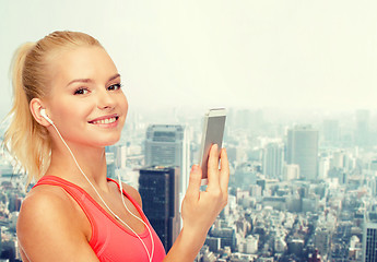 Image showing smiling sporty woman with smartphone and earphones