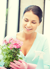 Image showing woman holding pot with flower and spray bottle