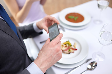 Image showing close up of couple with smartphones at restaurant